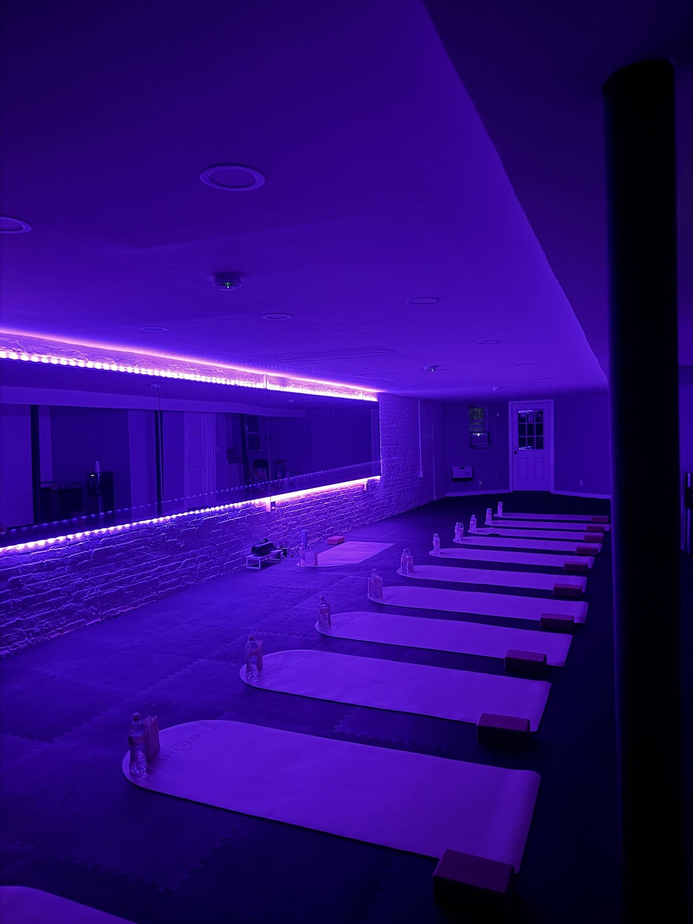 Yoga mats arranged in the purple-lit wellness studio